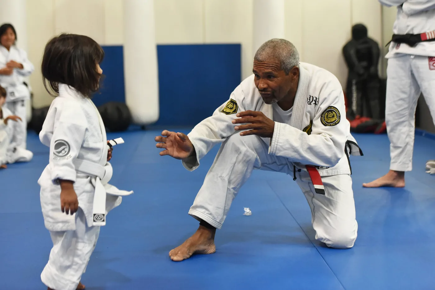Instructor helping a young child during Jiu-Jitsu class